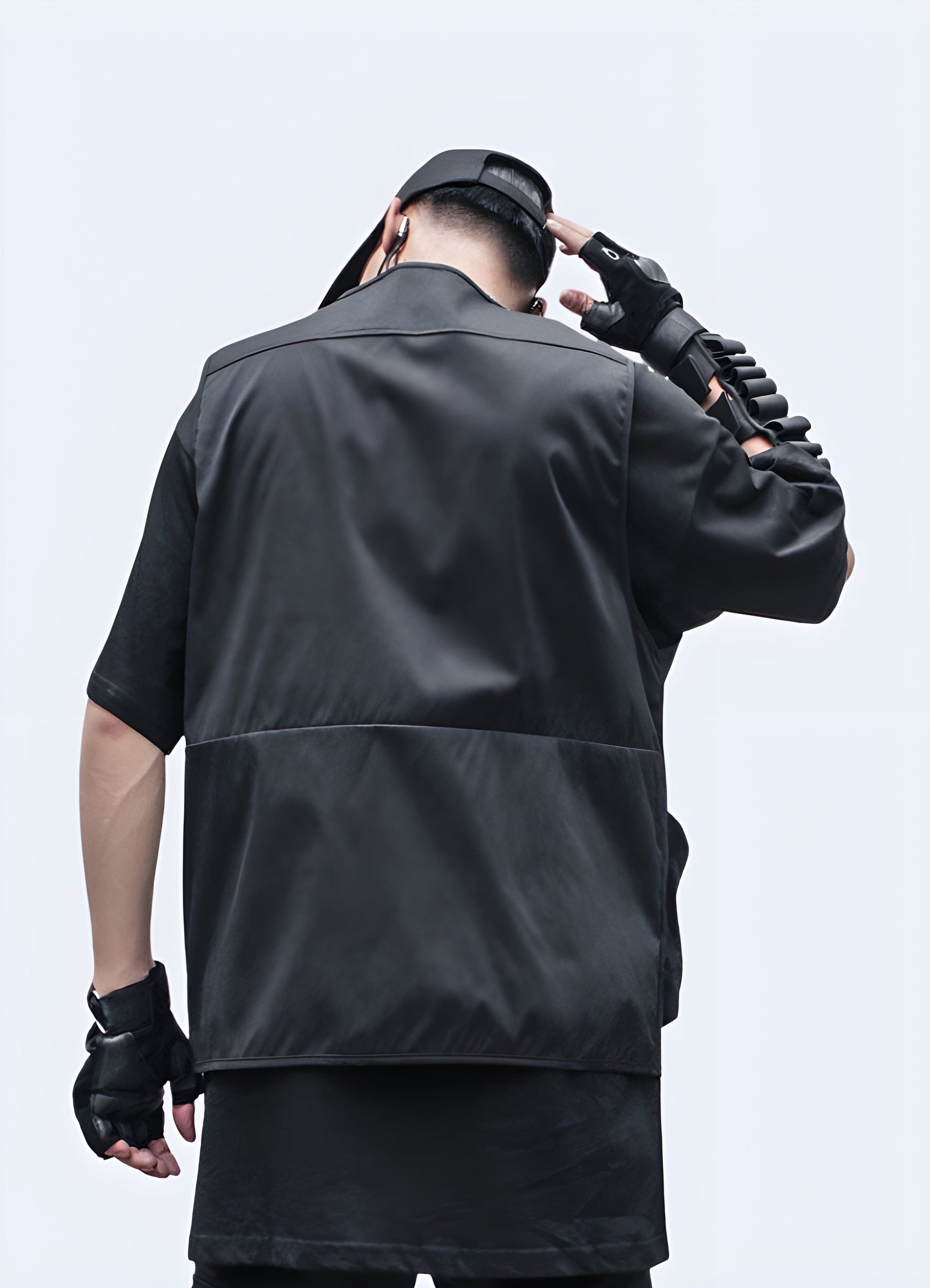 Rear view of a man wearing a black cargo vest featuring multiple storage pockets and adjustable straps, ideal for streetwear fashion and practicality.