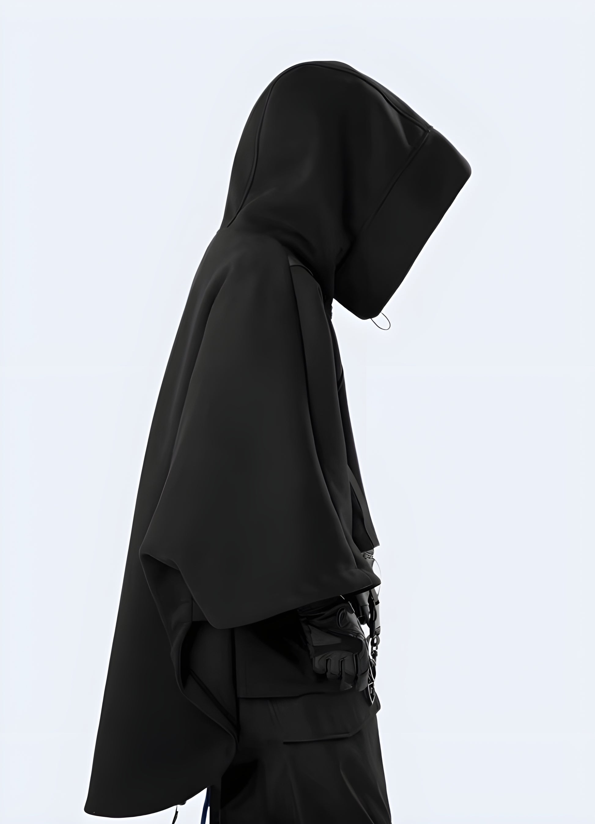 Man wearing a black functional hoodie, side view, in the UK—designed with utility features, a modern techwear aesthetic, and a comfortable fit for everyday urban wear.