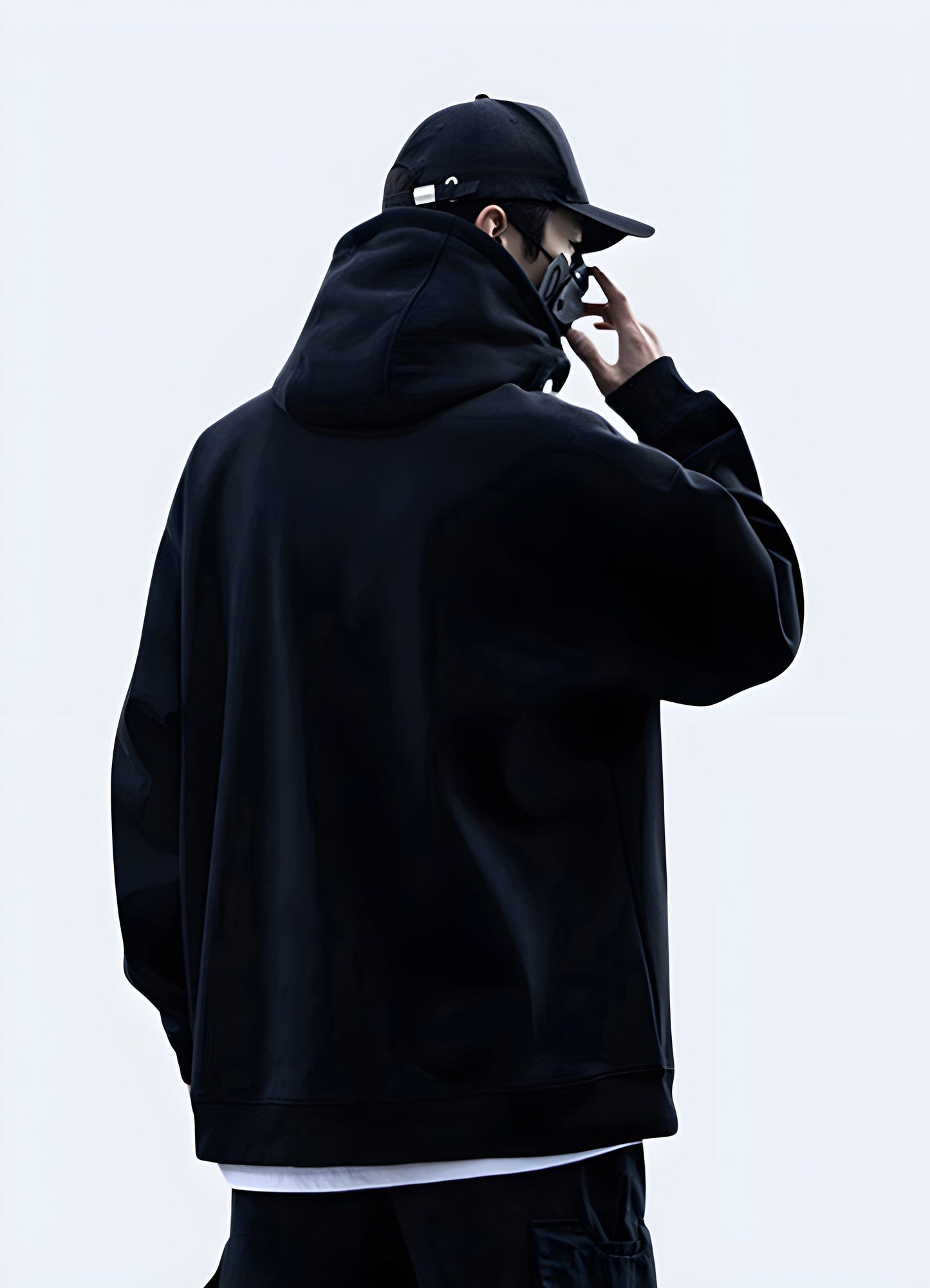 Back and side view of a man wearing a sleek black techwear goth hoodie in the UK, showcasing its unique design.