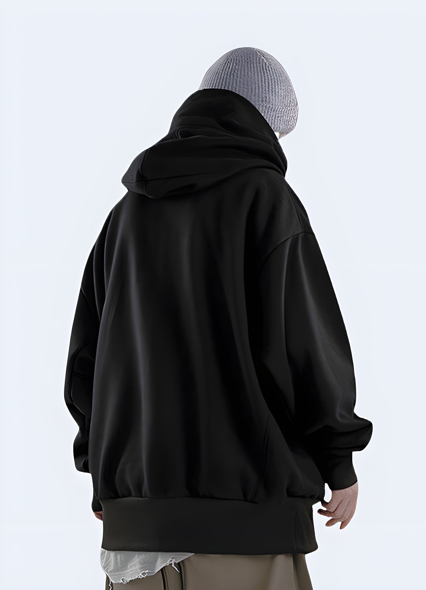 A man wearing a black high collar hoodie, displaying the back view of the hoodie in the UK.