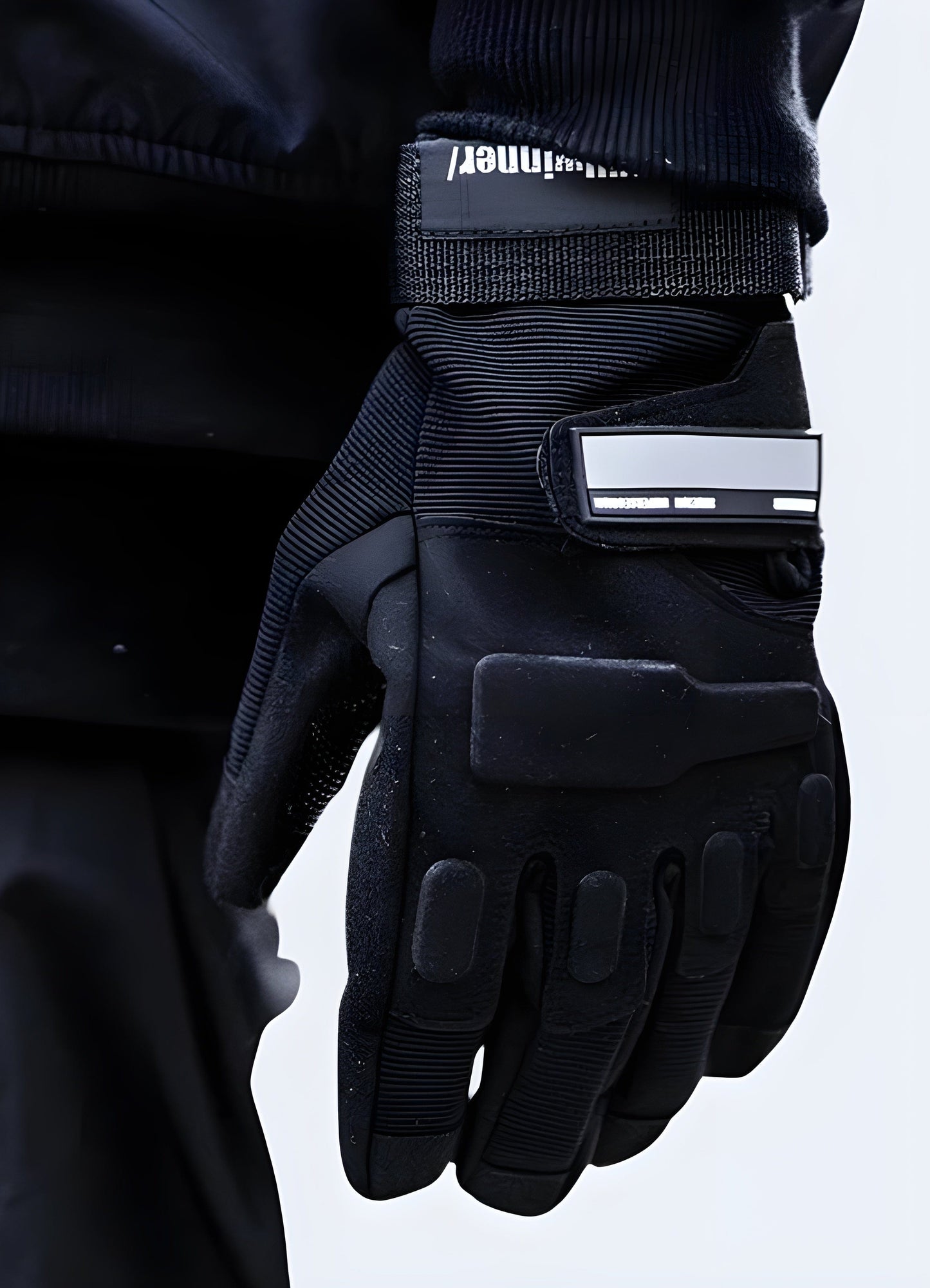 Front view of reflective gloves worn by a person. The gloves feature prominent reflective strips along the fingers and sides, with a sleek design and snug fit.