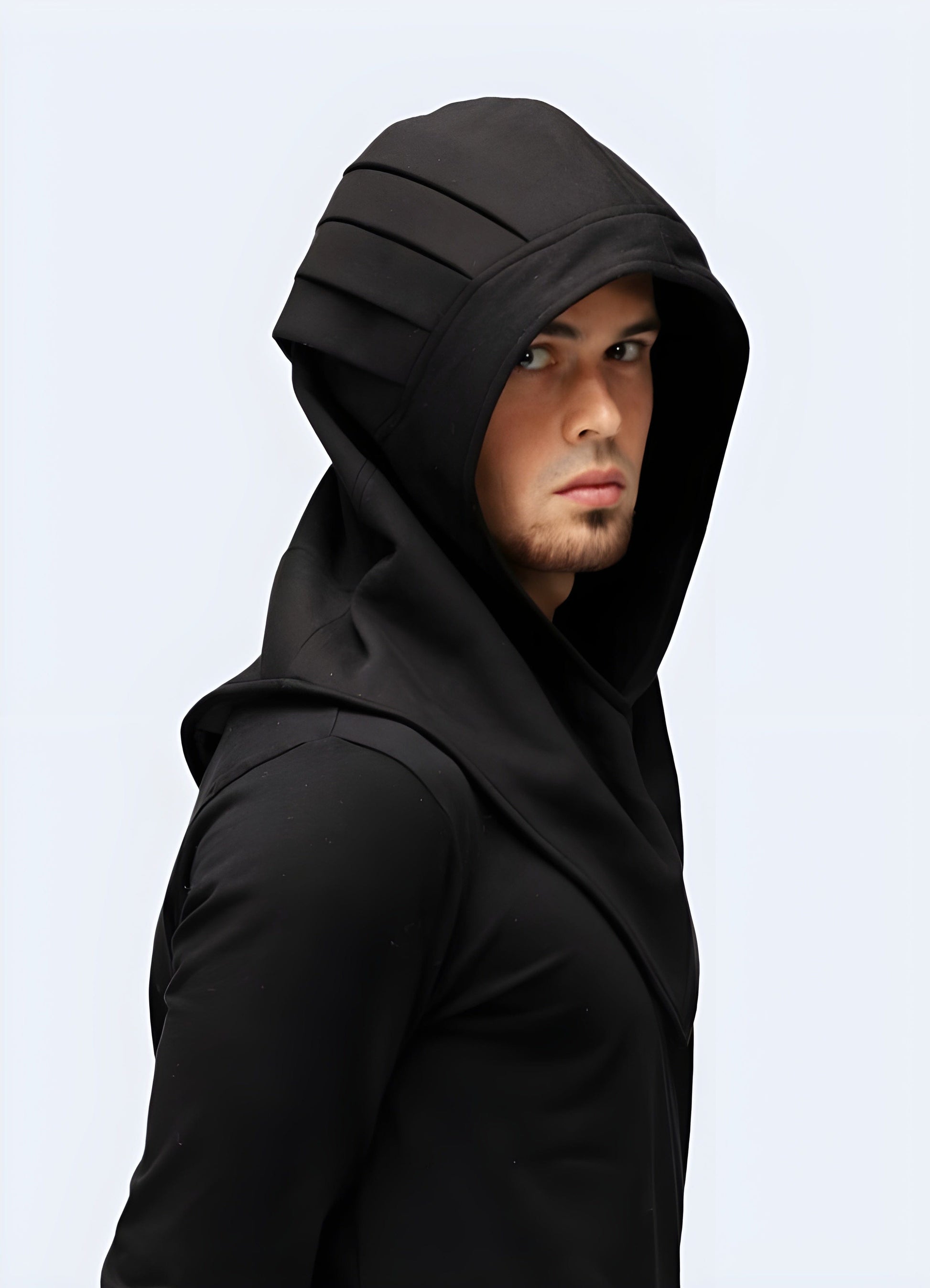 Man wearing a fashionable black techwear hood with a futuristic design, showcasing a side view of the garment in a UK setting.