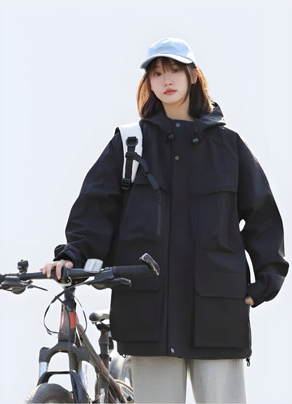 Front view of a model wearing a black hooded cargo jacket, showcasing its sleek design, multiple pockets, and protective hood, perfect for UK consumers seeking a fashionable and functional outerwear option.