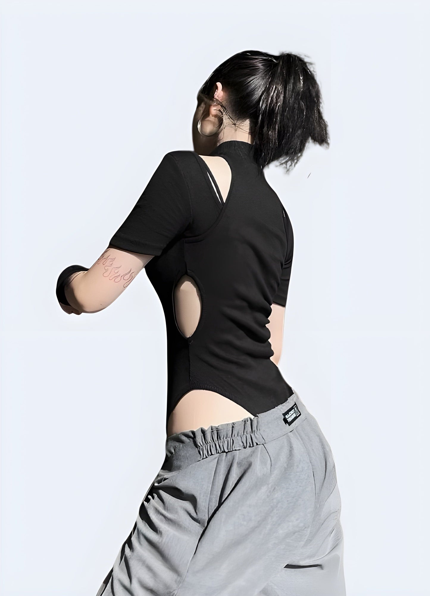 Back view of a woman in a black techwear leotard, highlighting the garment's unique design and functionality for UK techwear enthusiasts.