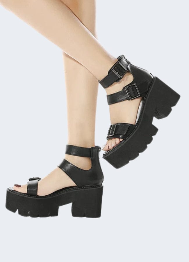  Side view of a woman wearing black chunky-heeled sandals. Fashionable and comfortable footwear choice for women in the UK.