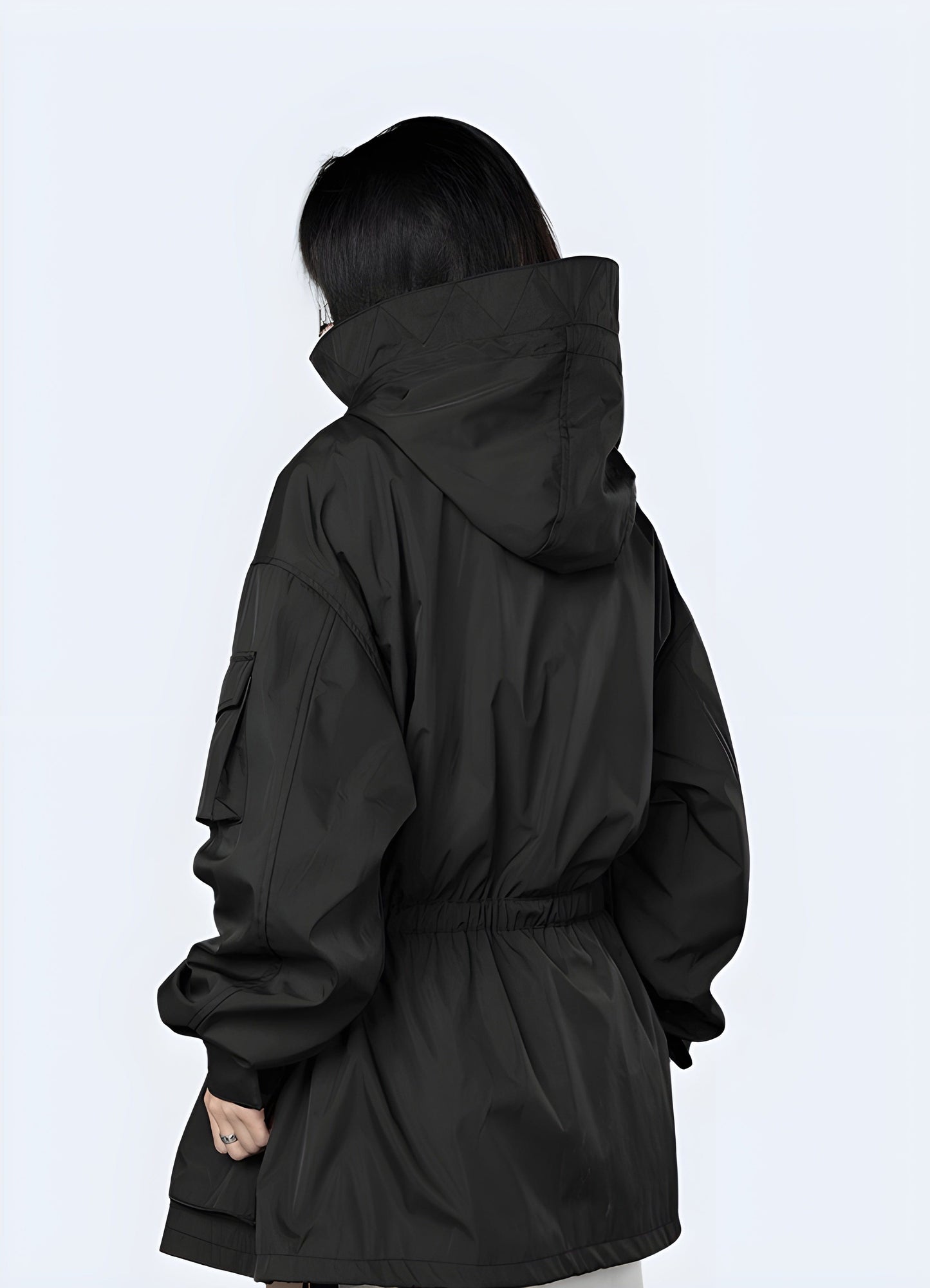 Back view of a woman wearing a women's techwear parka, showcasing its functional features and modern silhouette for city life in the UK.