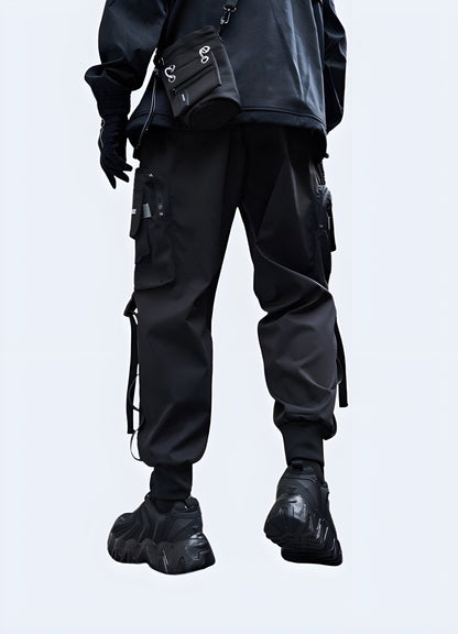  Back view of a man wearing durable techwear cargo trousers, showcasing the garment's practical design and modern aesthetics, perfect for the UK techwear scene.